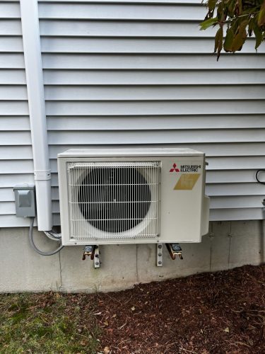 Mitsubishi heat pump installed on side of house.  This heat pump is eligible for a MassSave heat loan and a rebate